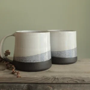 Two matte and speckled glaze porcelain mugs on wood